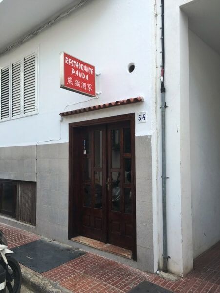 Un edificio blanco con un cartel rojo que dice restaurante.