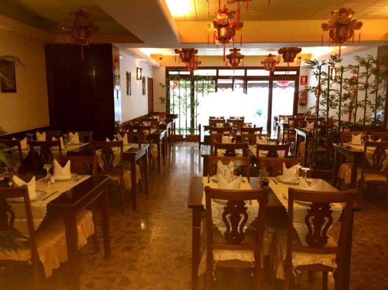 Un restaurante con mesas y sillas y faroles colgando del techo.