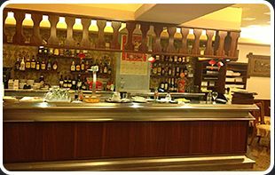 Un bar con barandilla de madera y botellas en el estante.