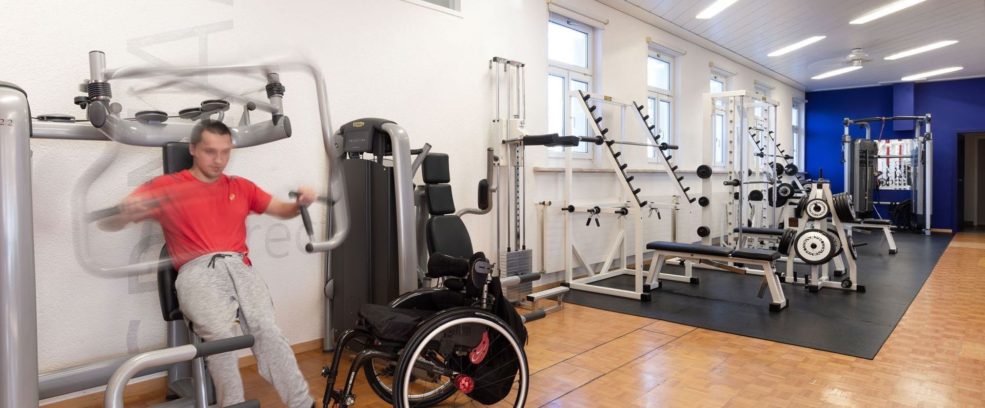 Ein Mann im Rollstuhl benutzt ein Gerät in einem Fitnessstudio.