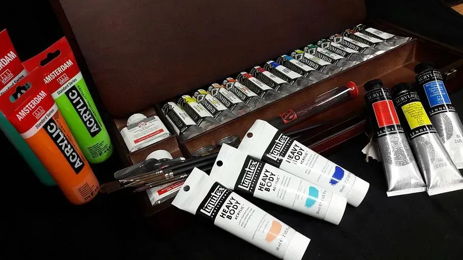 Des tubes de peinture près d'une boîte qui contient elle aussi des petits tubes de peinture