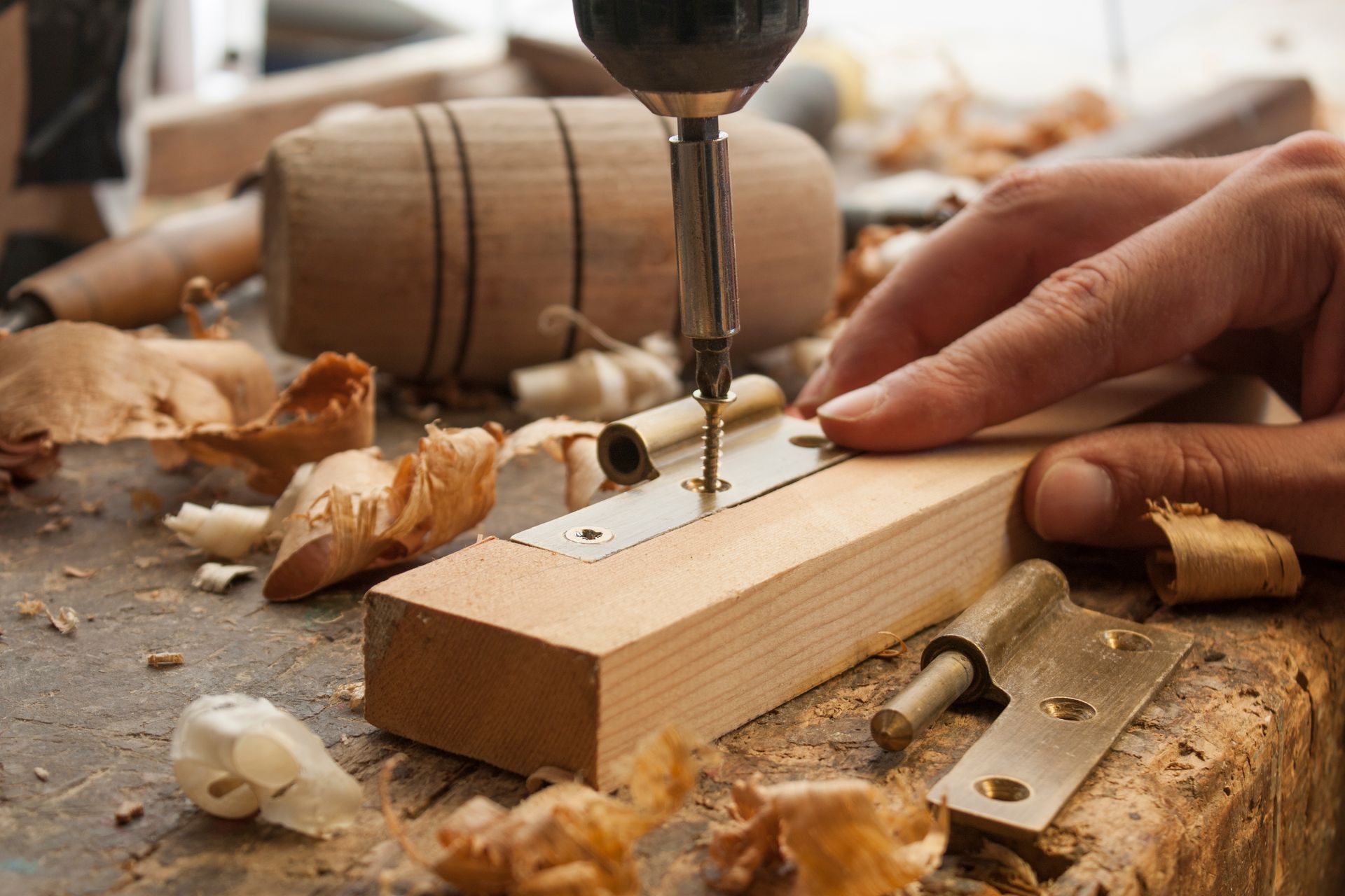Un menuisier en train de visser une vis dans un bloc de bois avec une visseuse