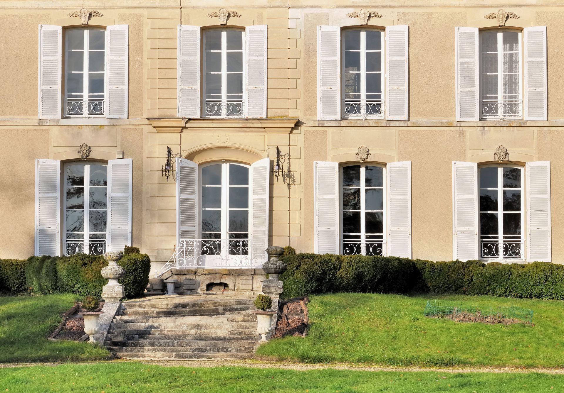 Grand bâtiment d'un domaine avec plusieurs fenêtres aux volets battants blancs