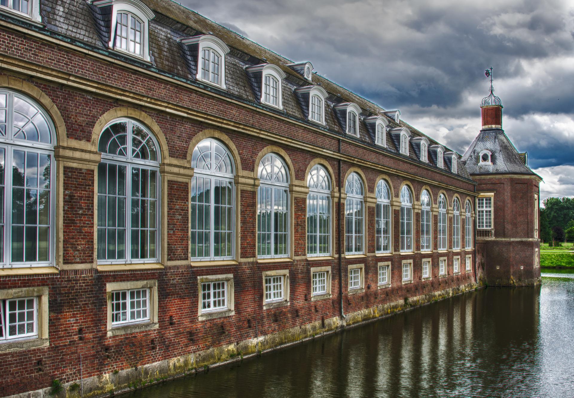 Grand bâtiment style château au bord de l'eau avec de grandes fenêtres