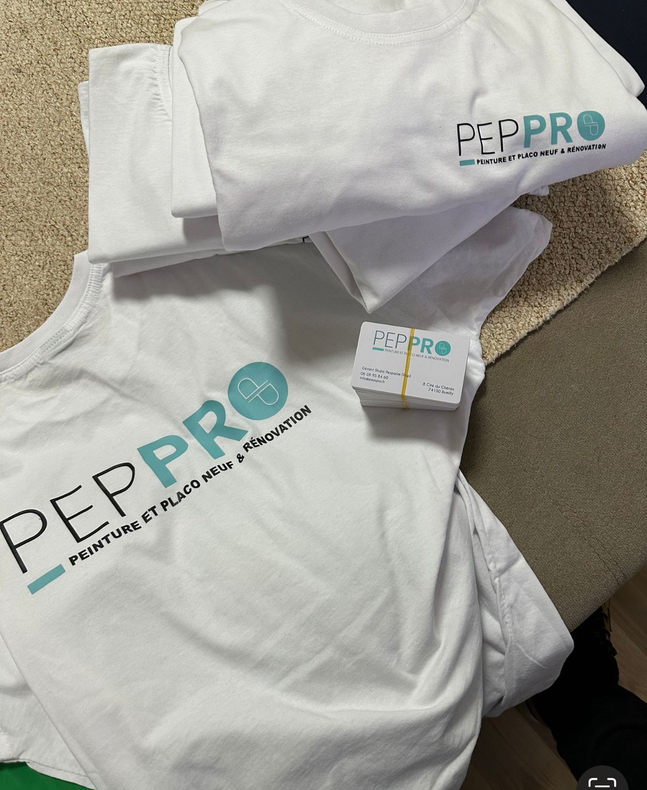 Photo prise du dessus de tee-shirts et d'une carte de visite de l'entreprise PEP PRO