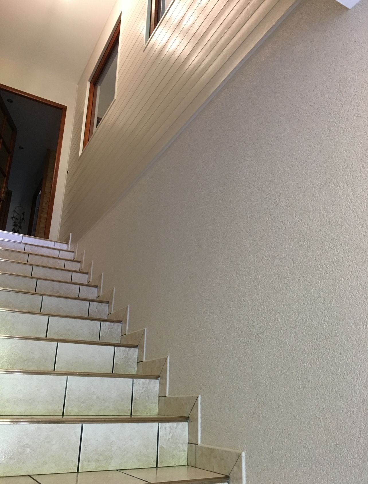 Photo d'un escalier après la restauration des murs qui sont en plâtre blanc.