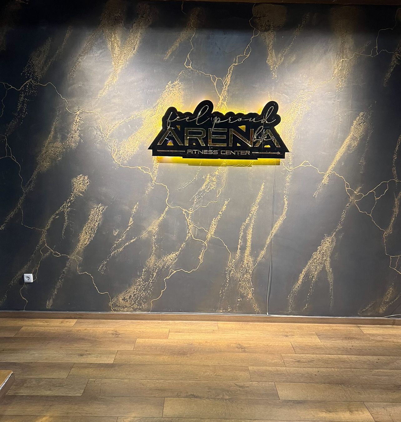Photo d'un mur bleu avec des effets jaunes avec le logo de l'entreprise Feel Proud Arena Fitness Center.
