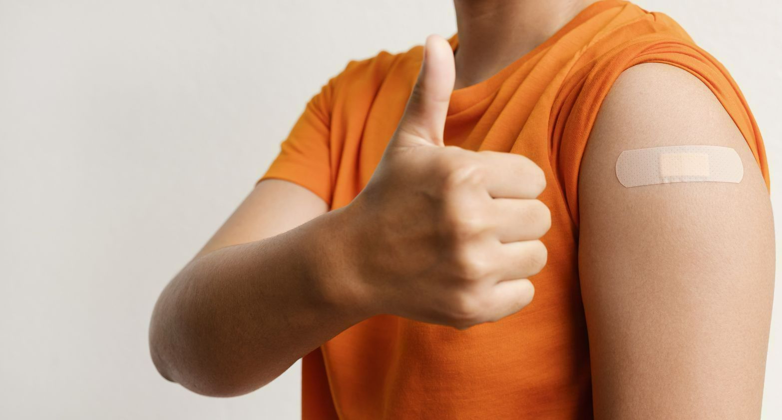 Photo d'une personne avec le pouce en l'air montrant un pansement sur le haut de son bras