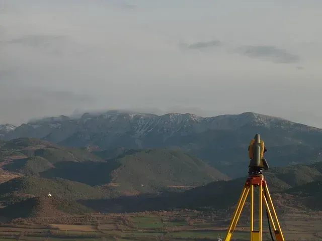Un trípode con una cámara delante de una cadena montañosa.