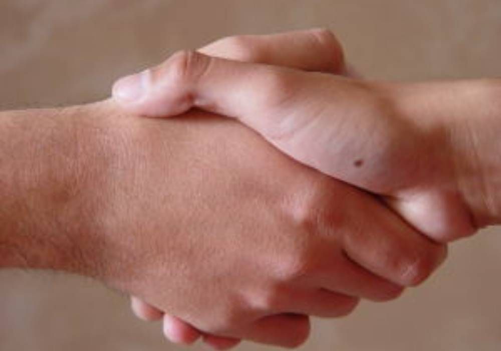 Un primer plano de dos personas dándose la mano en una mesa.