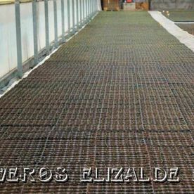 Zona de césped con rejilla metálica en la parte superior, al lado de un edificio.