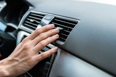 Réglage manuel d'une grille d'aération du tableau de bord d'une voiture sur un panneau intérieur gris