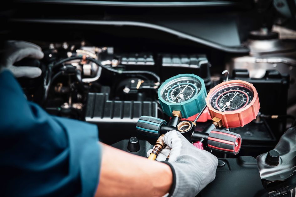 Un mécanicien ganté utilise des jauges pour effectuer l'entretien du moteur d'une voiture dans un atelier.