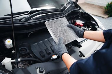 Un mécanicien ganté installe un filtre à air dans une voiture.