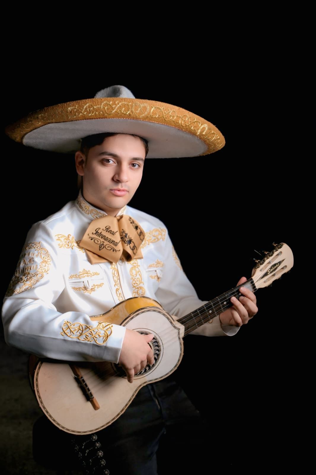 Hombre con un gran sombrero sosteniendo un banjo sobre un fondo negro.