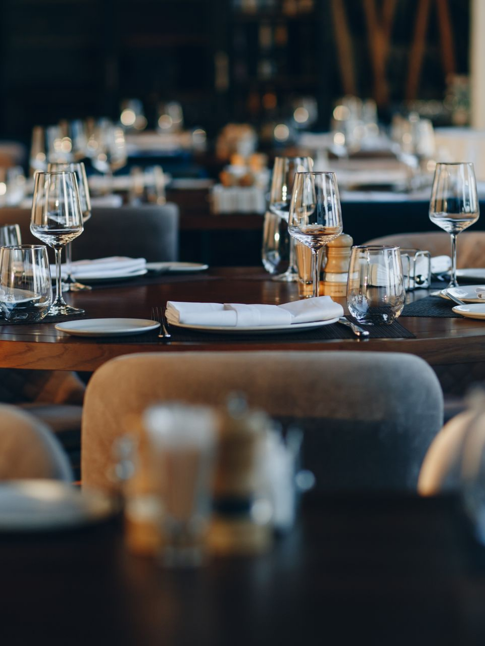 Dressage de table au restaurant avec verres, assiettes et serviette.