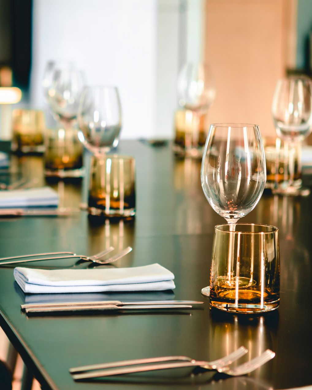 Dressage de table avec verres à vin, verres ambrés, couverts et serviettes.