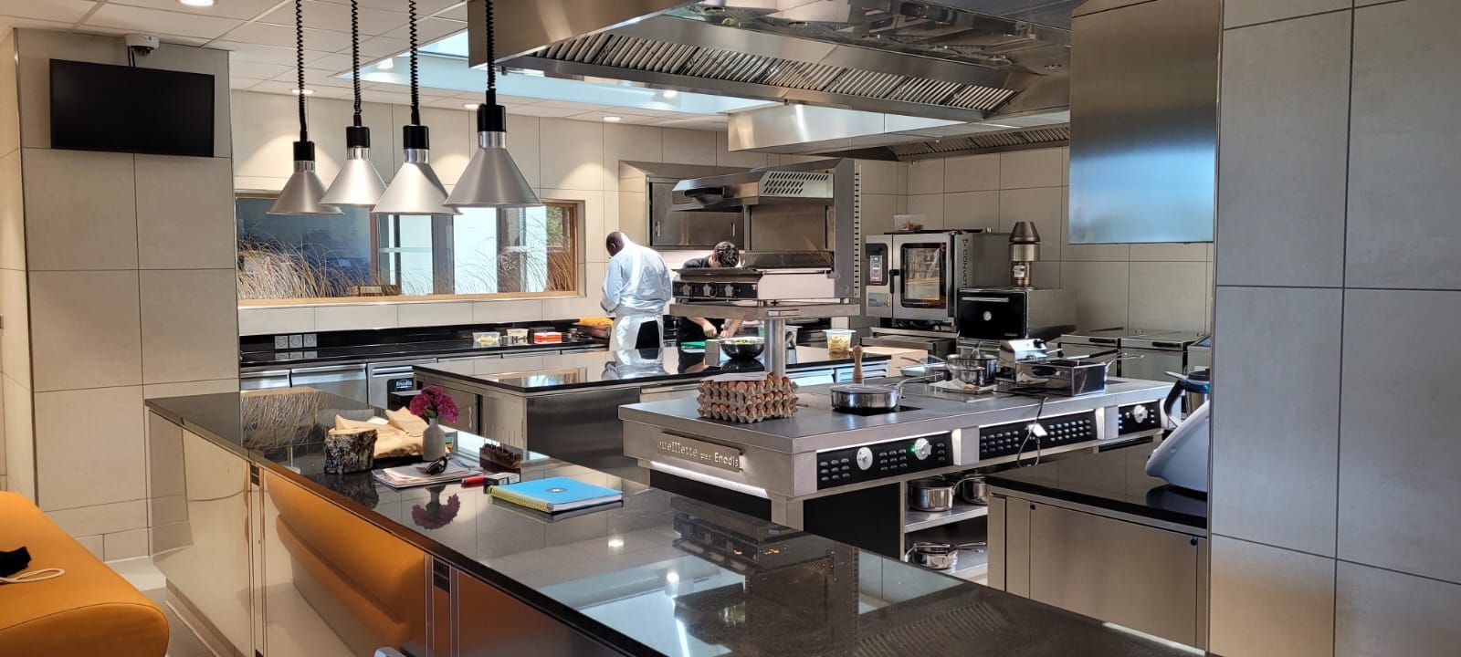 Cuisine professionnelle équipée d'appareils en acier inoxydable : four, cuisinière et hotte.