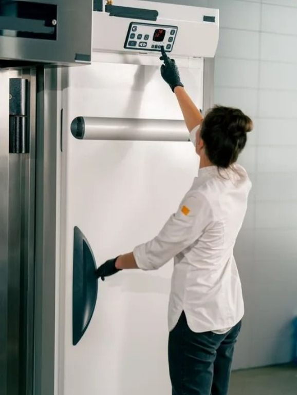 Personne qui actionne un grand four et en règle les commandes.