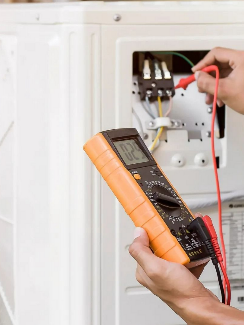 Personne utilisant un multimètre pour tester les connexions électriques d'un climatiseur.