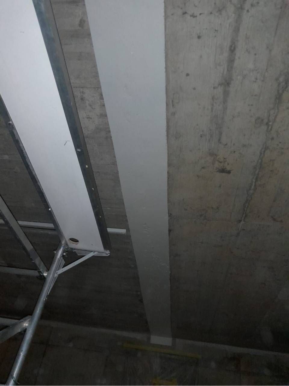 Un échafaudage soutient un plafond en béton auquel est fixée une longue bande blanche.