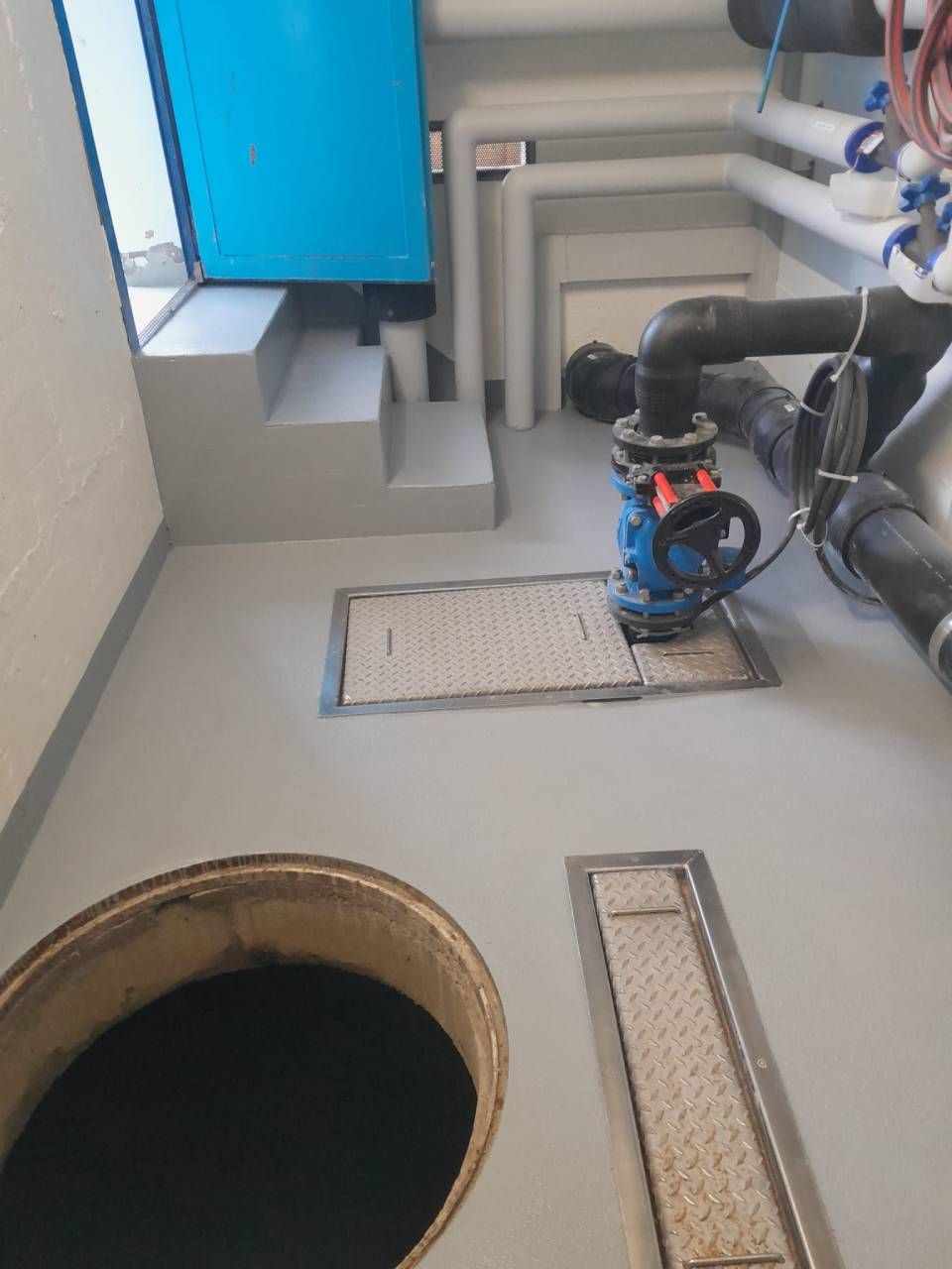 Piscine carrelée vide, avec des carreaux bleus et blancs.