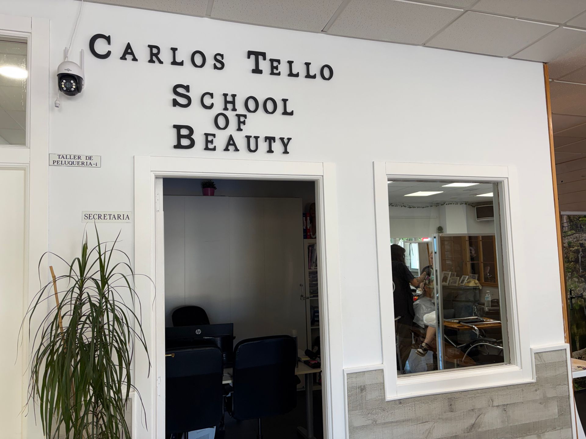 Entrada a la Escuela de Belleza Carlos Trejo con puerta abierta y escaparate.