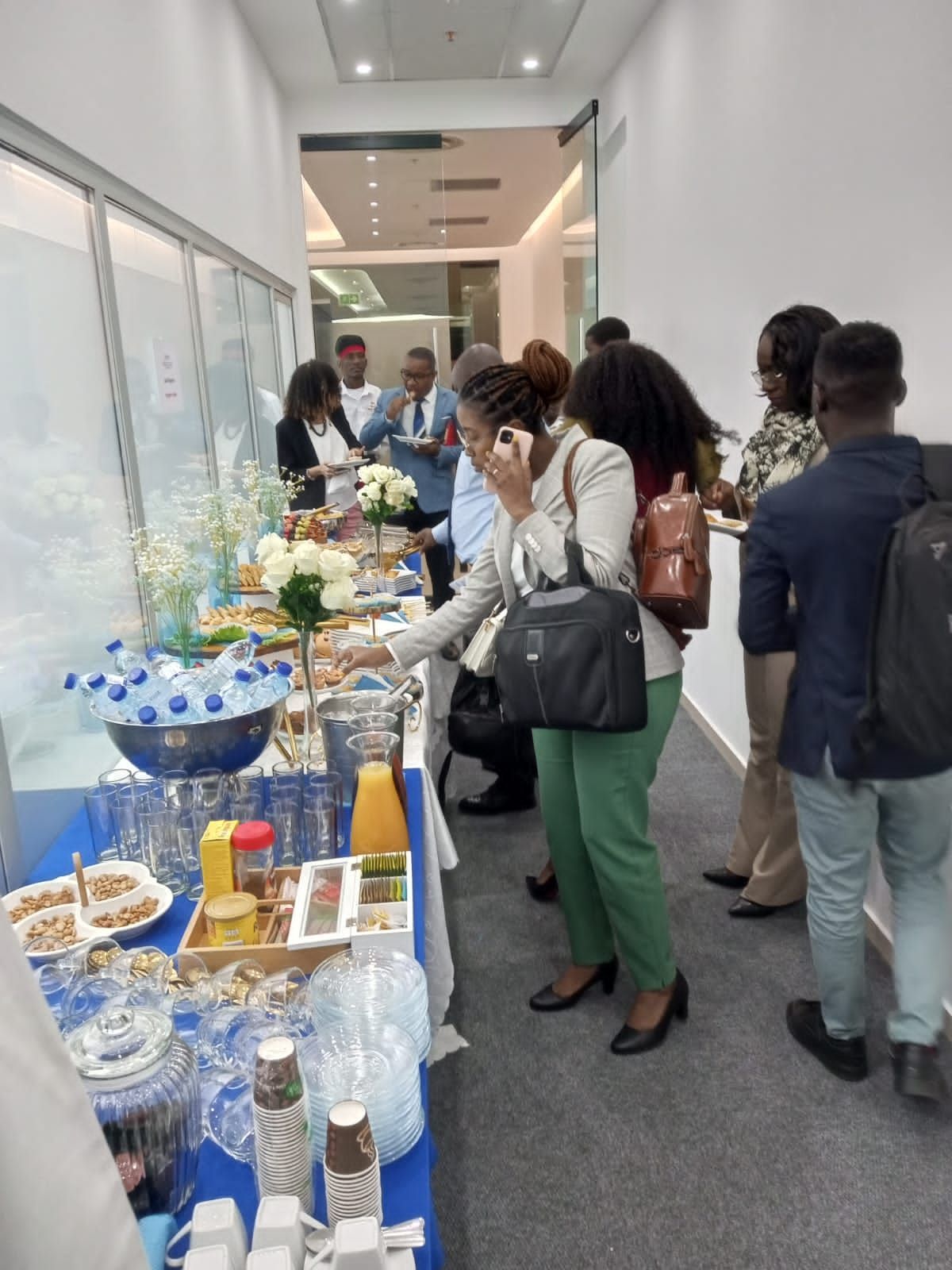 a group of people standing around a table with food and drinks