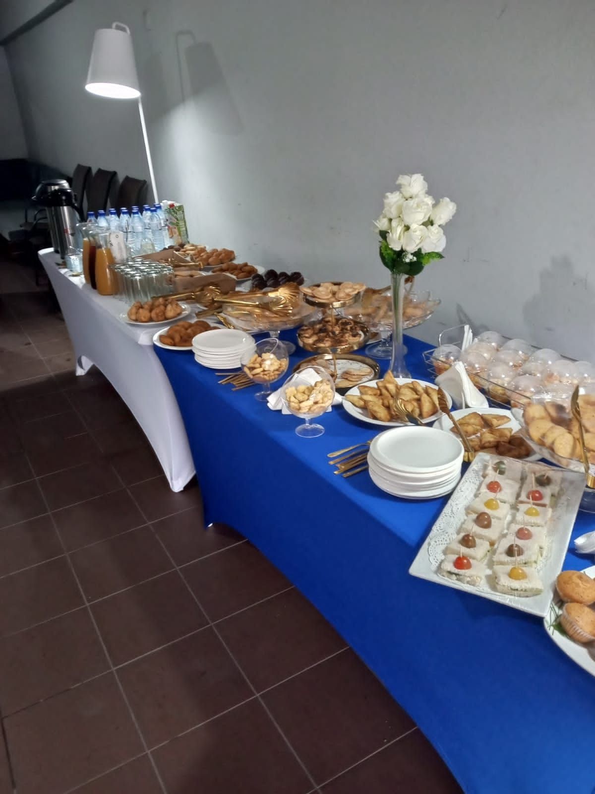 a buffet table with a blue table cloth and lots of food on it