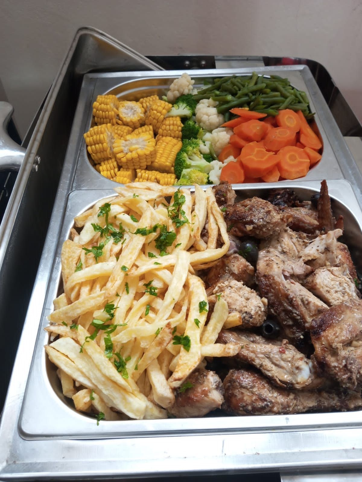 a buffet tray filled with french fries , meat and vegetables .