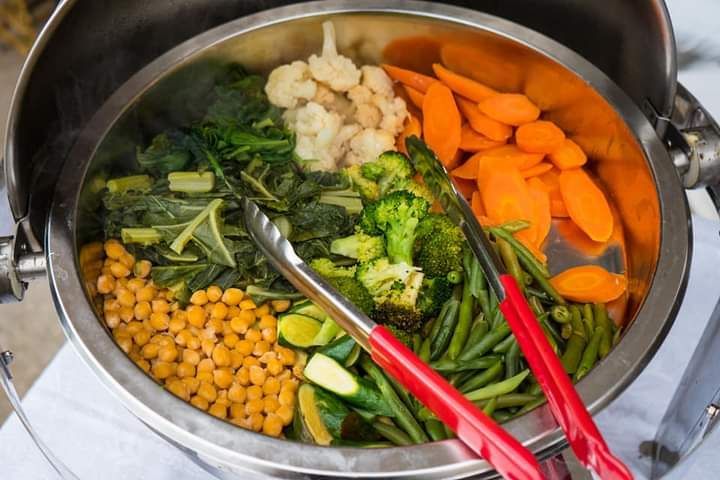 uma tigela de legumes com uma pinça.