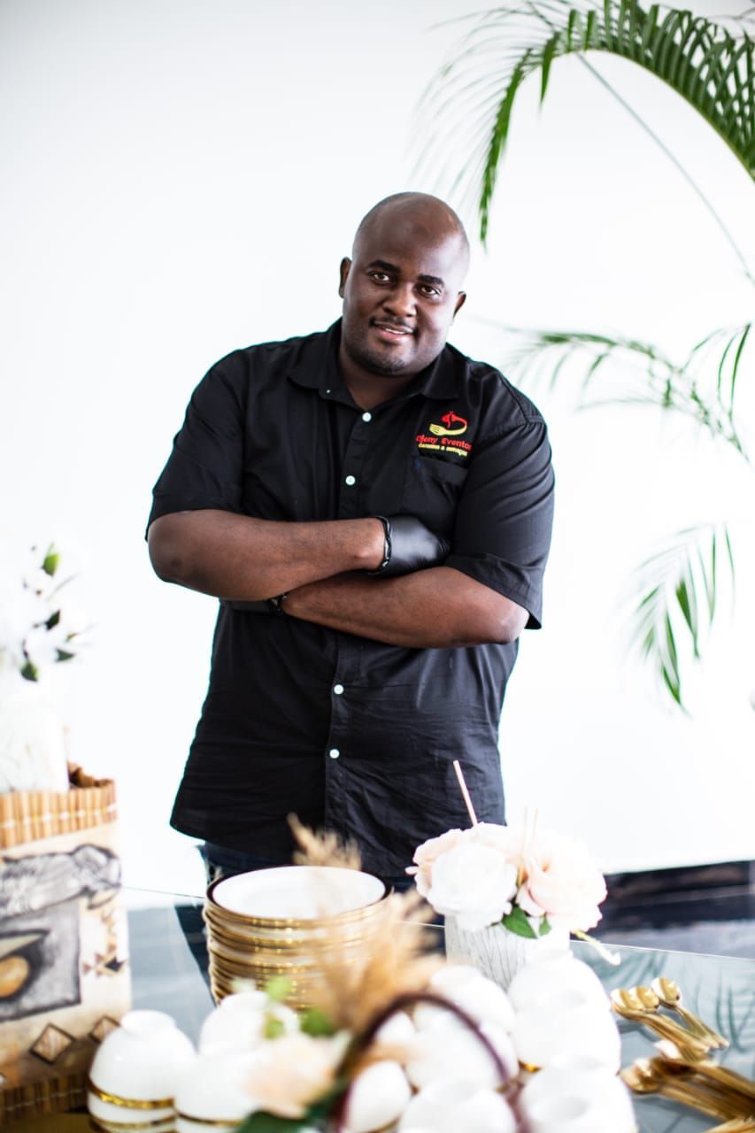 a man is standing in front of a table with his arms crossed .