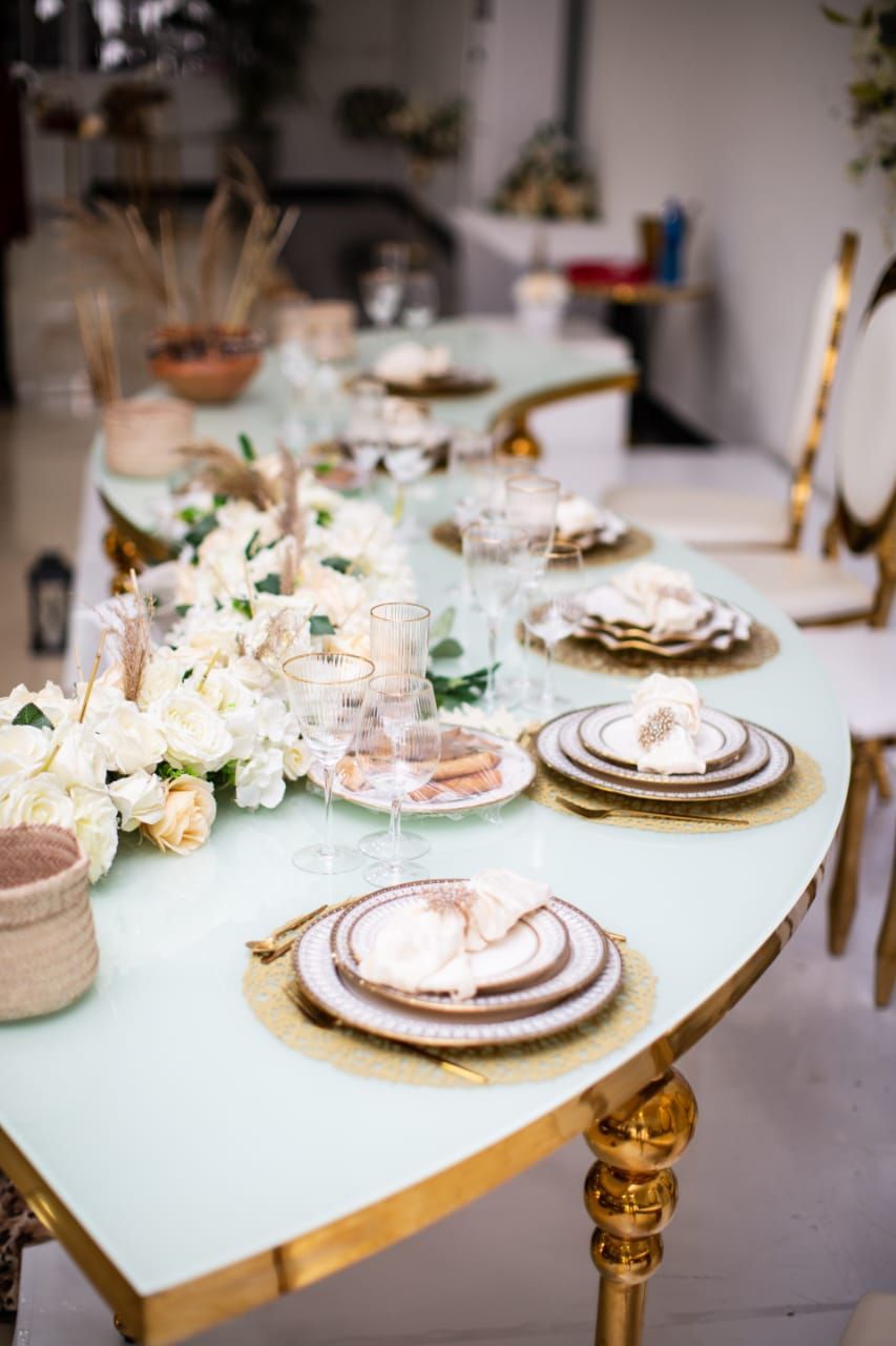 uma longa mesa com pratos, copos e flores.