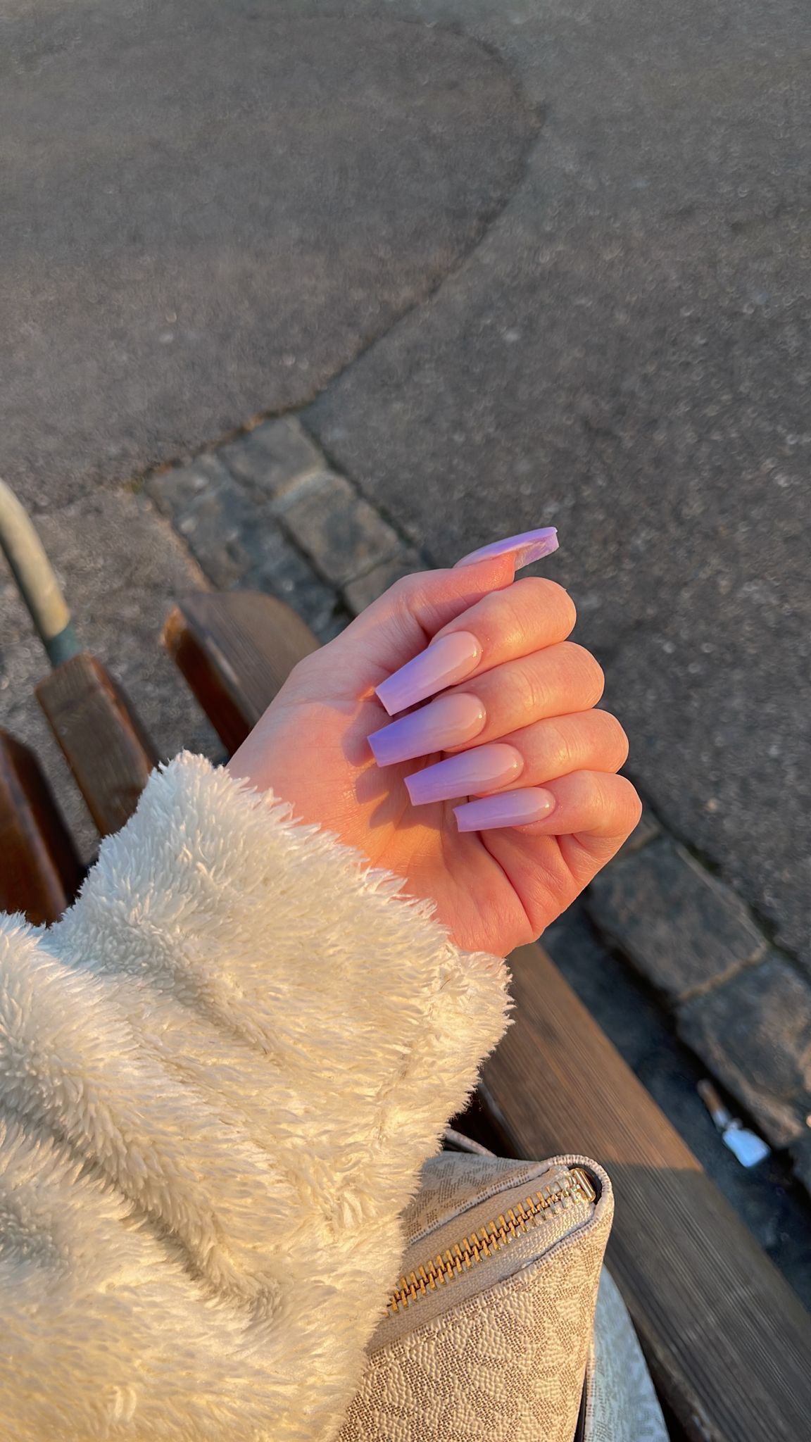 Eine Nahaufnahme von Händen mit mandelförmigen, glänzend dunkelrot lackierten Nägeln und zwei Ringen an der oberen Hand.