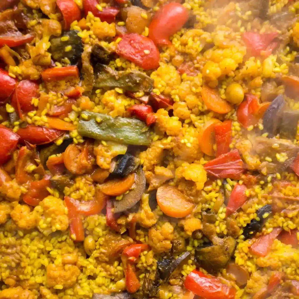 Plato de arroz amarillo con pimientos rojos y verduras.