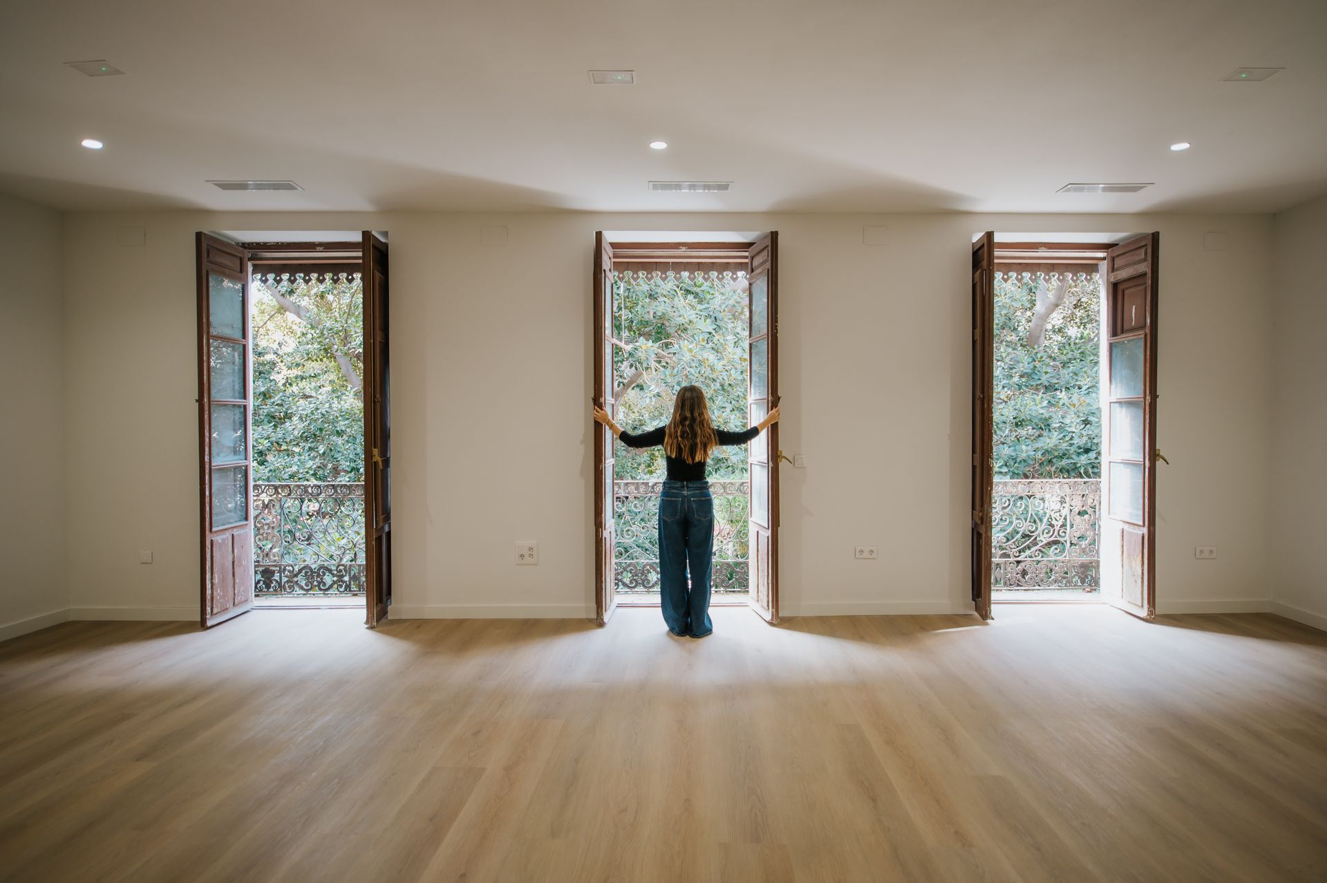 Foto desde el interior de una casa a tres ventanales que dan a una vista frondosa