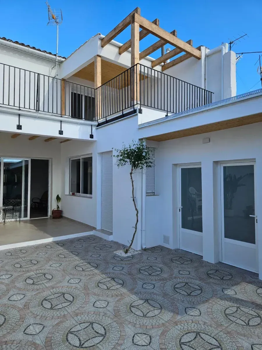 Una casa blanca con un balcón y un árbol delante.