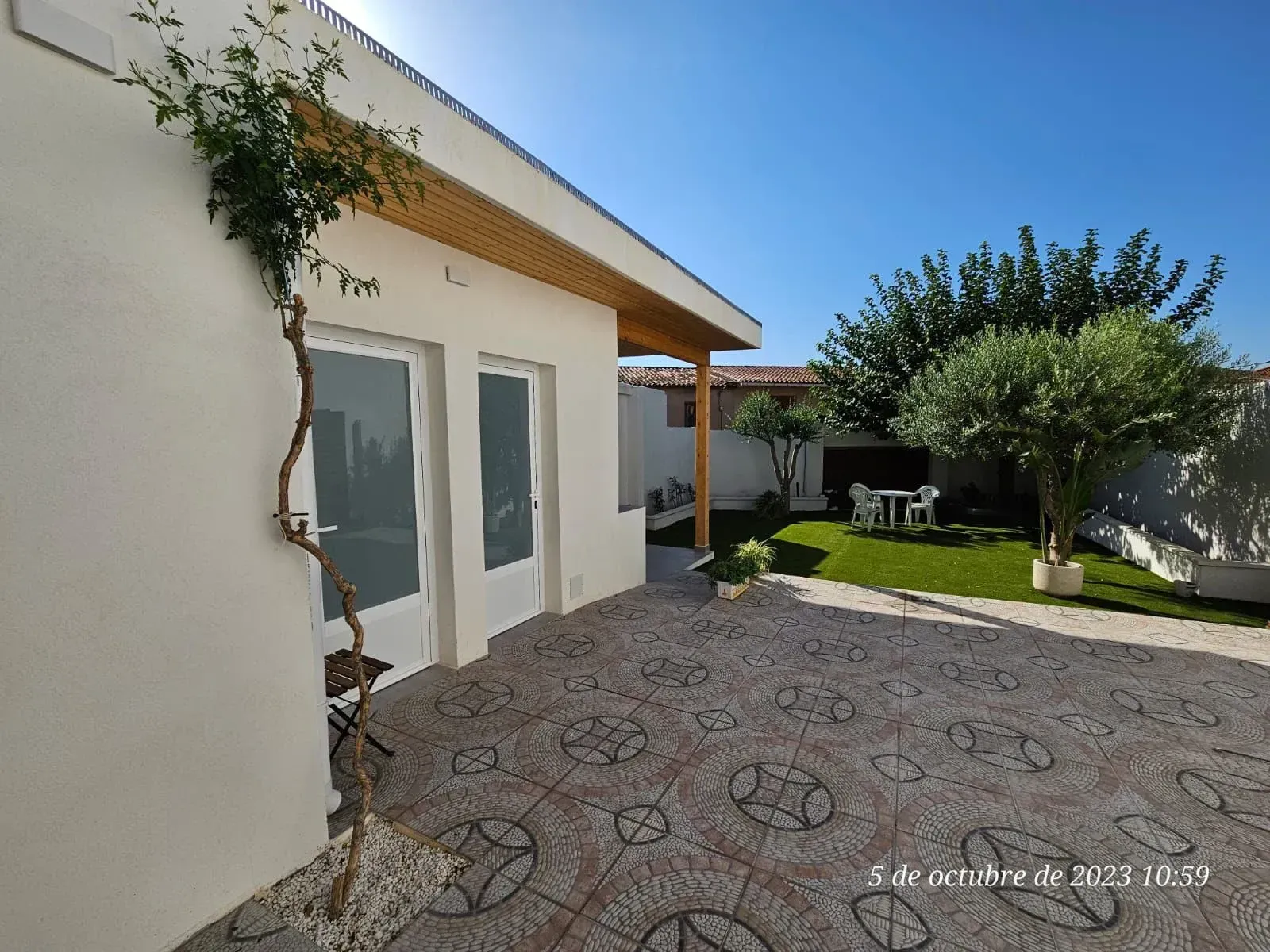 Una casa blanca con un patio y un árbol delante.