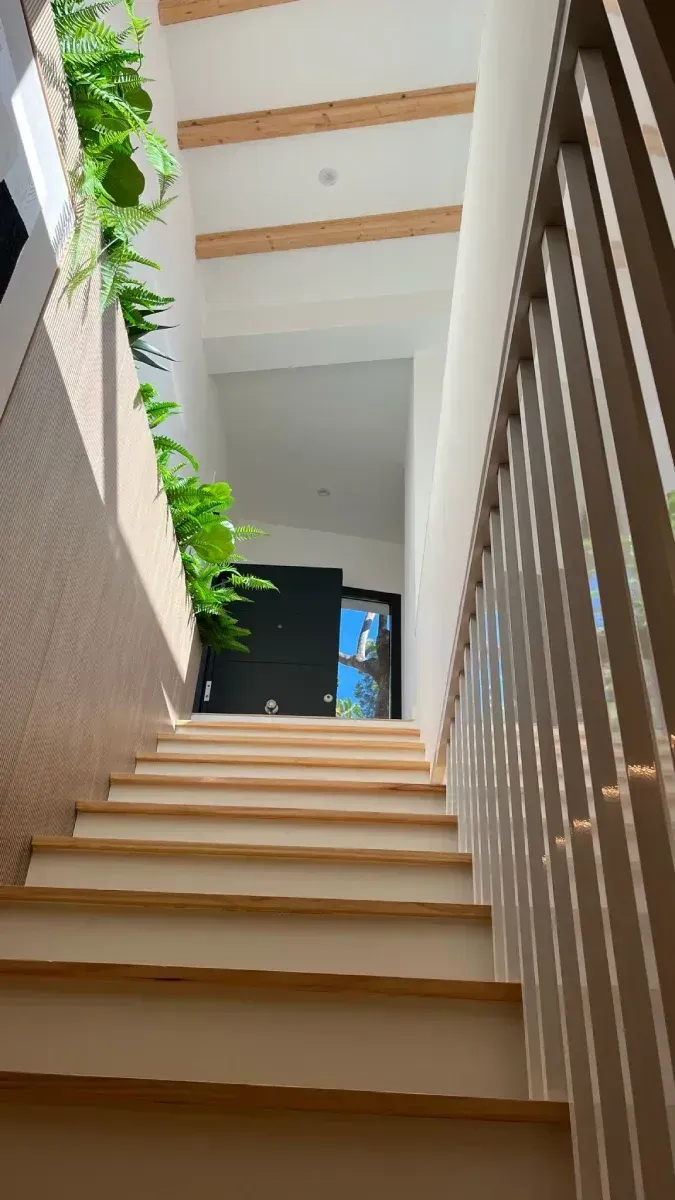 Mirando hacia abajo por un conjunto de escaleras de madera con una barandilla de metal.