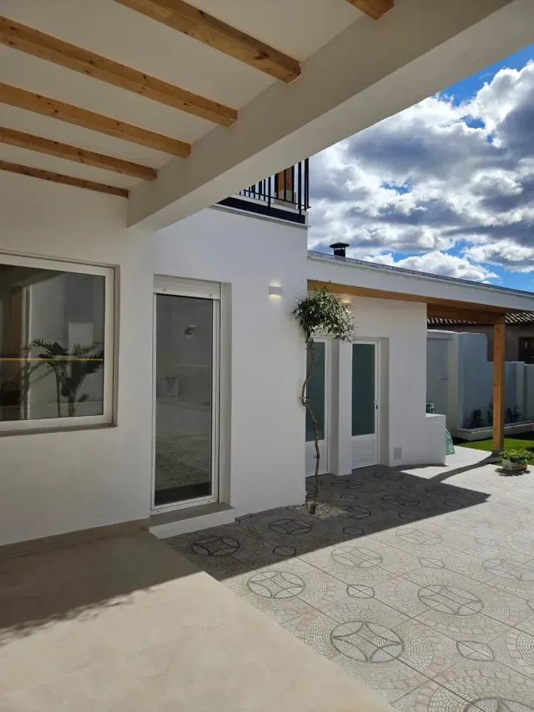 Una casa blanca con techo de madera y patio