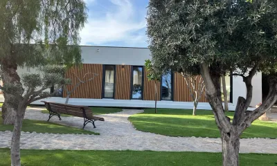 Una fotografía de una casa con un banco delante de ella.