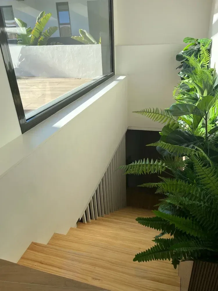 Una escalera con una ventana y una planta en maceta.
