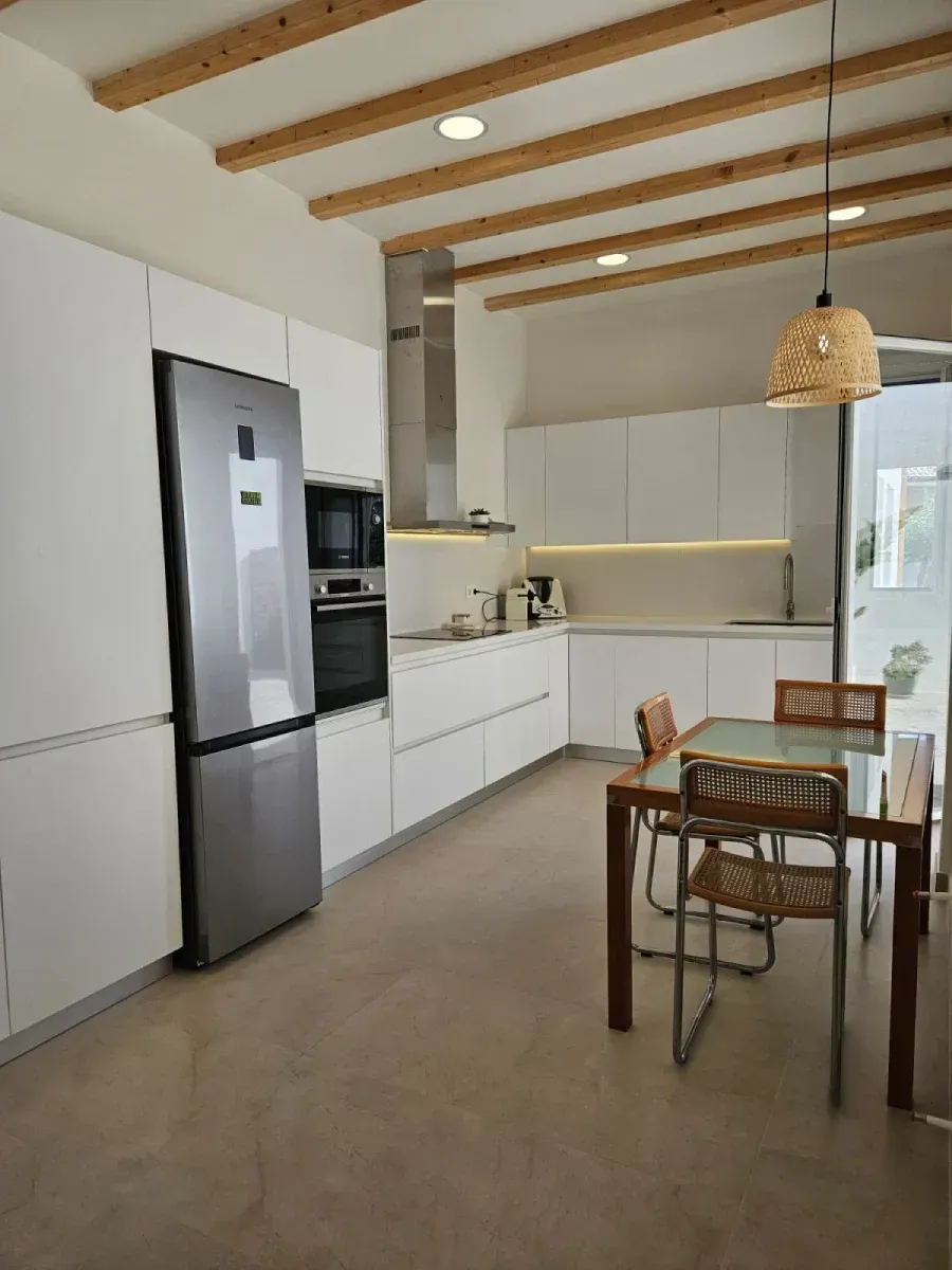 Una cocina con mesa y sillas y un refrigerador.