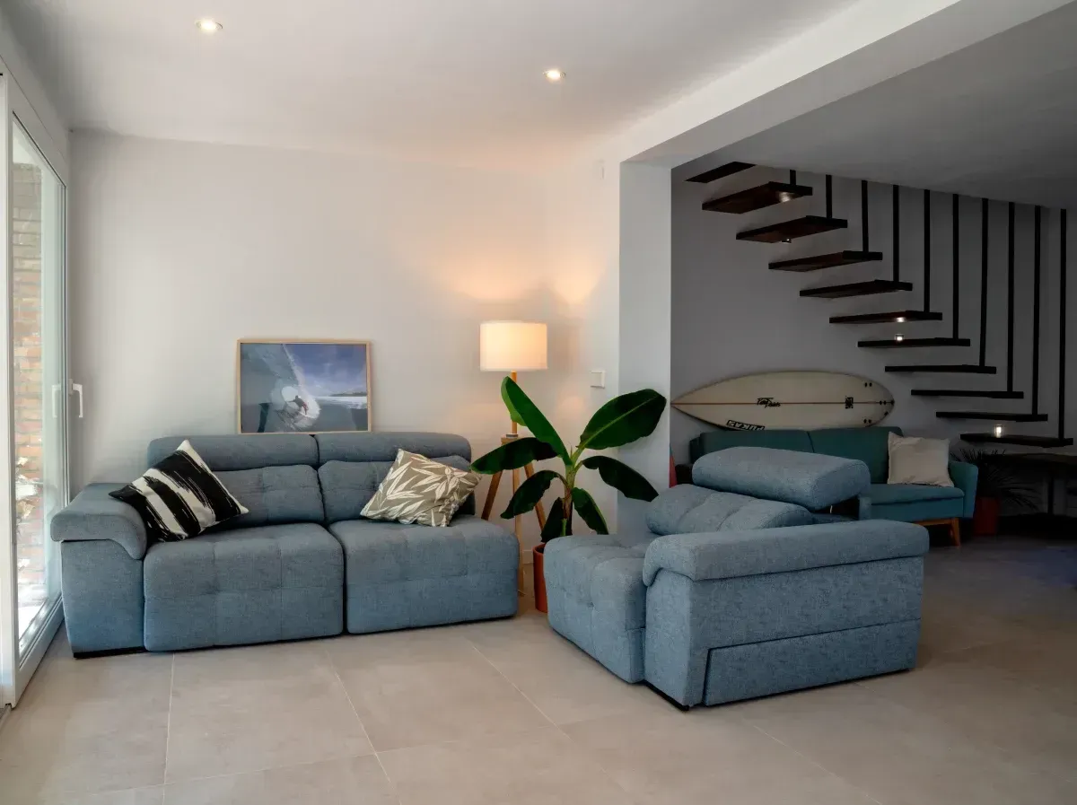 Una sala de estar con un sofá azul y dos sillas.