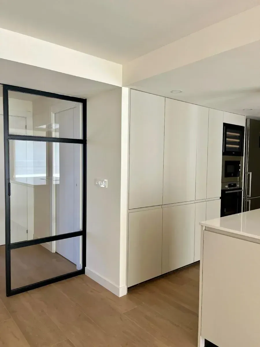 Una cocina con gabinetes blancos y electrodomésticos de acero inoxidable.