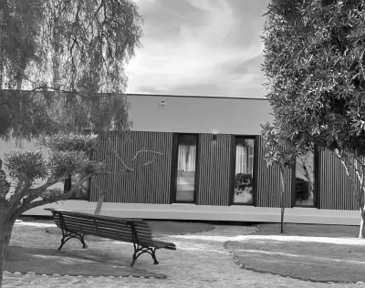 Una fotografía en blanco y negro de una casa con un banco delante de ella.