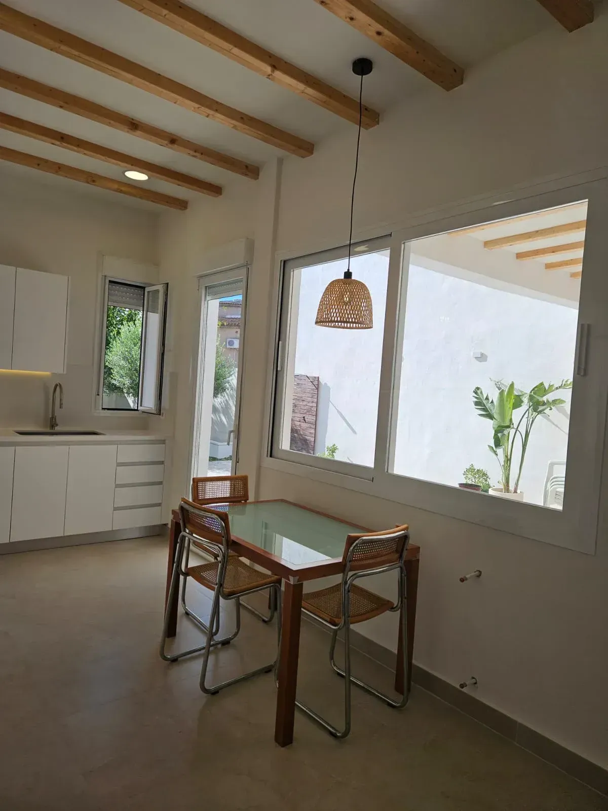 Una cocina con una mesa y sillas frente a una ventana.