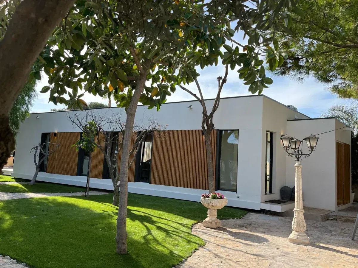 Una casa blanca con algunos árboles delante de ella.