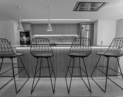 Una foto en blanco y negro de una cocina con taburetes.