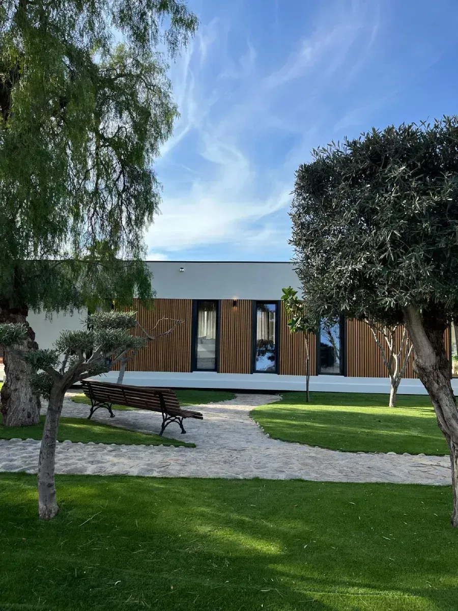 Un parque con árboles y un banco frente a una casa.